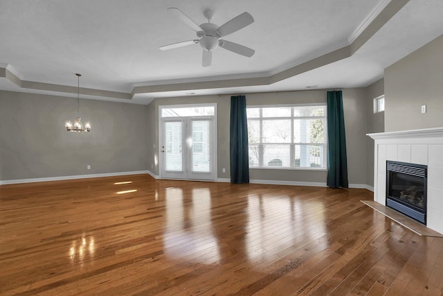 unfurnished living room with hardwood / wood-style flooring, a raised ceiling, and a tile fireplace