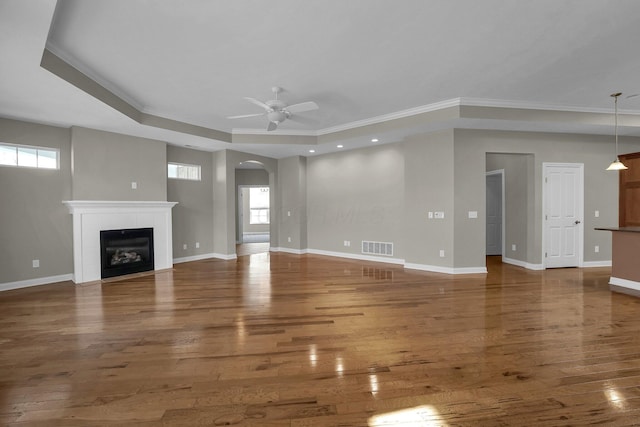 unfurnished living room featuring plenty of natural light, a tile fireplace, dark hardwood / wood-style floors, and ceiling fan