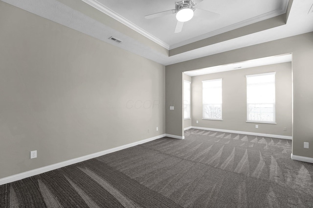 empty room featuring crown molding, ceiling fan, a raised ceiling, and dark carpet