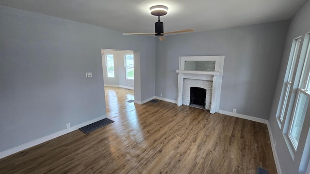 unfurnished living room with hardwood / wood-style floors, ceiling fan, and a fireplace