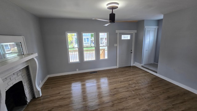 interior space featuring ceiling fan, a fireplace, and dark wood-type flooring