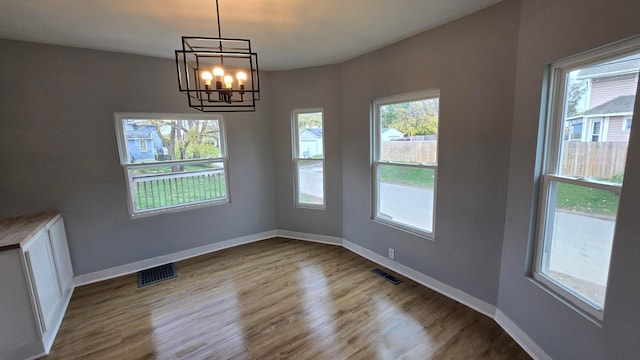 unfurnished dining area with light wood-type flooring and an inviting chandelier