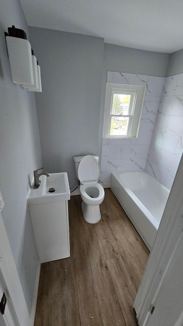 bathroom with a tub, hardwood / wood-style floors, vanity, and toilet