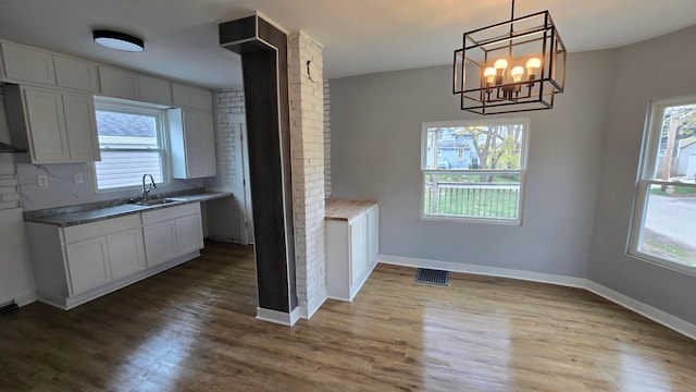 kitchen featuring pendant lighting, white cabinetry, sink, and hardwood / wood-style flooring