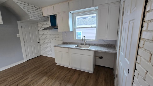 kitchen with wall chimney range hood, sink, dark hardwood / wood-style floors, tasteful backsplash, and white cabinetry