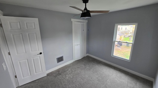 unfurnished bedroom featuring ceiling fan, a closet, and dark colored carpet