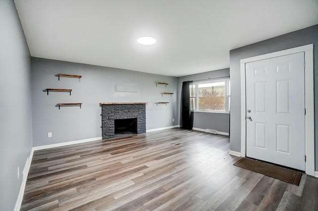 unfurnished living room featuring hardwood / wood-style floors and a stone fireplace