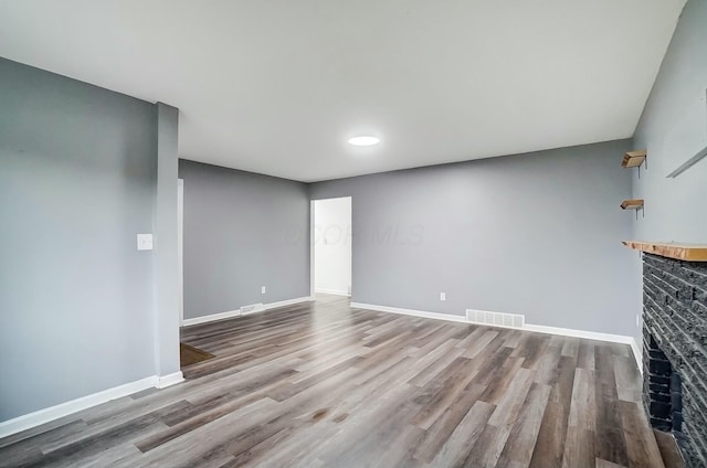 unfurnished living room featuring light wood-type flooring and a brick fireplace