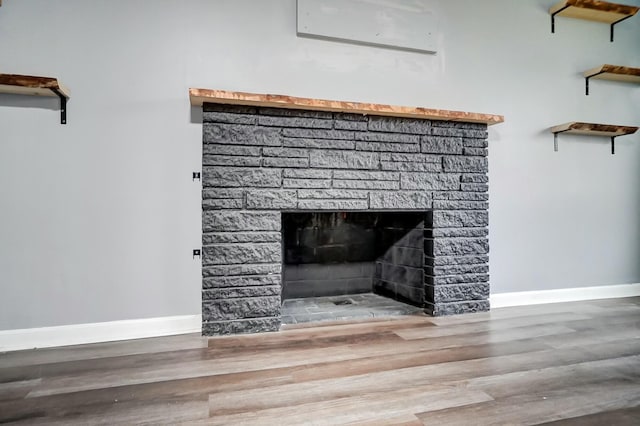 room details with wood-type flooring, a stone fireplace, and a wall mounted AC