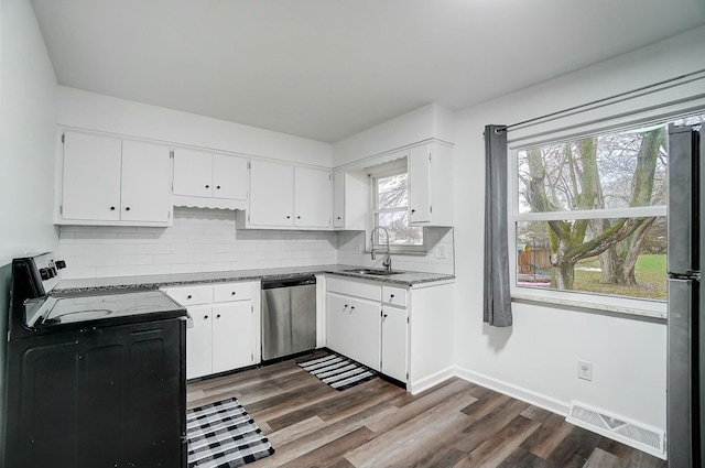 kitchen with dark wood-type flooring, sink, decorative backsplash, appliances with stainless steel finishes, and white cabinetry