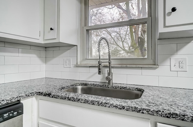 kitchen featuring decorative backsplash, sink, white cabinets, and stainless steel dishwasher