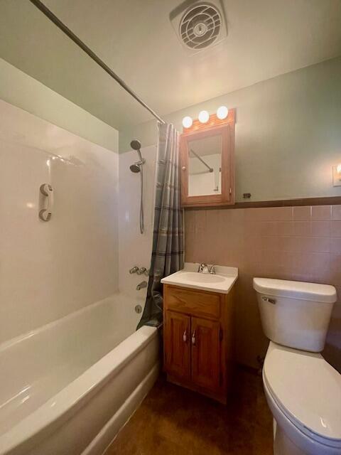 full bathroom with toilet, vanity, shower / tub combo with curtain, and tile walls