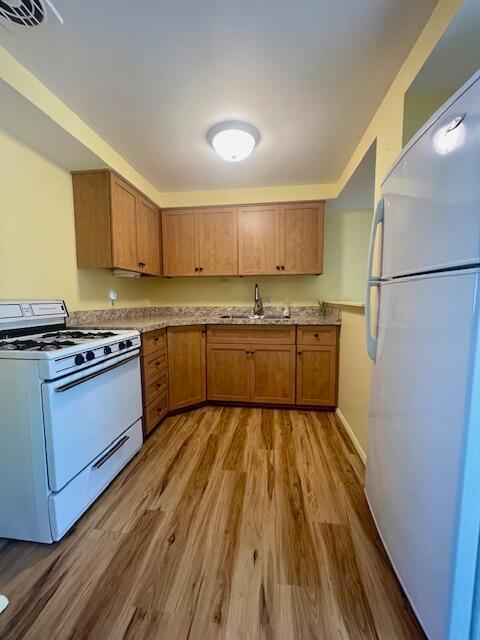 kitchen with hardwood / wood-style floors, white appliances, and sink