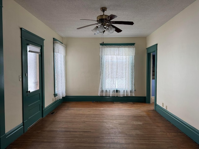 empty room with ceiling fan, dark hardwood / wood-style floors, and a textured ceiling