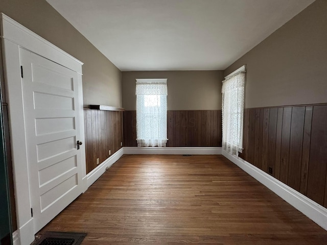 empty room with hardwood / wood-style flooring and wood walls