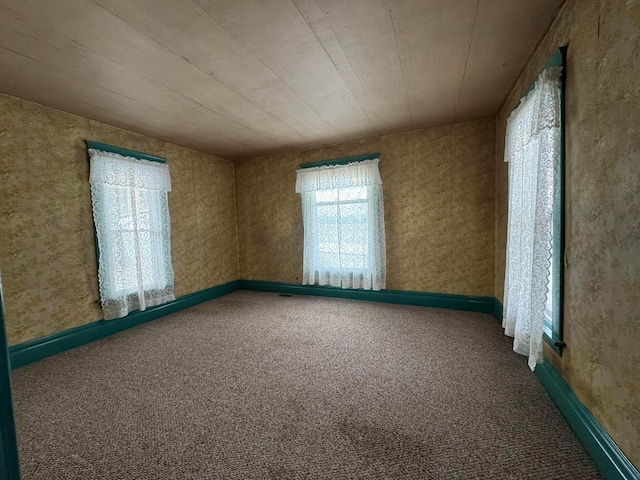 carpeted spare room featuring wood ceiling