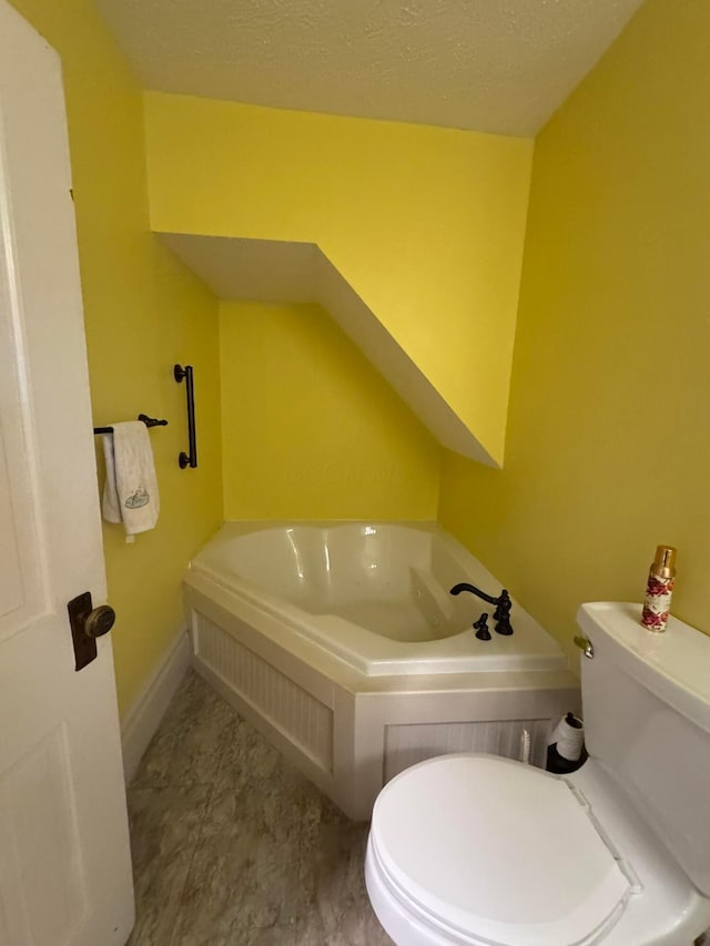 bathroom with a textured ceiling, toilet, and a tub