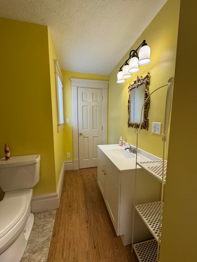 bathroom with hardwood / wood-style flooring, vanity, toilet, and a textured ceiling