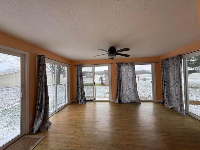 unfurnished sunroom featuring ceiling fan