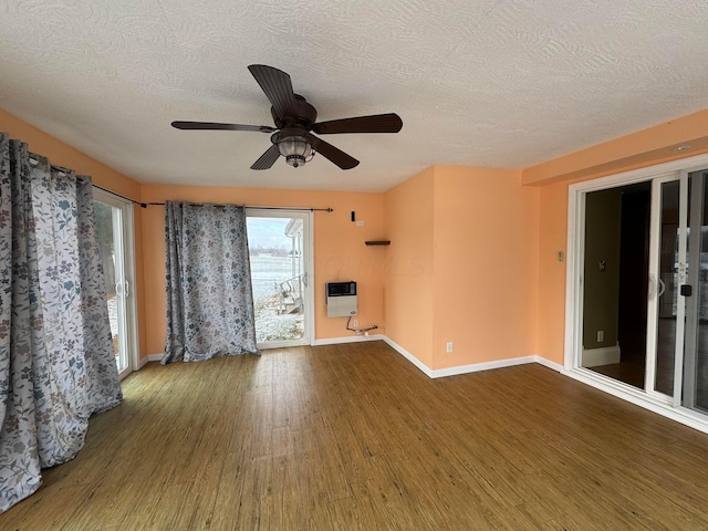 unfurnished living room with ceiling fan, hardwood / wood-style floors, heating unit, and a textured ceiling