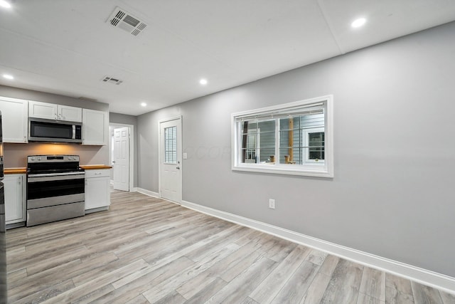 kitchen featuring butcher block countertops, white cabinetry, stainless steel appliances, and light hardwood / wood-style flooring