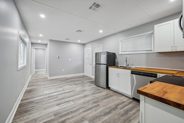 kitchen featuring butcher block counters, white cabinetry, sink, stainless steel appliances, and light hardwood / wood-style floors