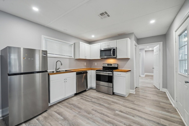 kitchen featuring white cabinetry, light hardwood / wood-style flooring, wooden counters, and appliances with stainless steel finishes