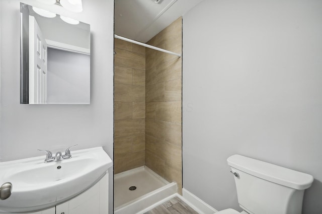 bathroom featuring a tile shower, sink, toilet, and hardwood / wood-style floors