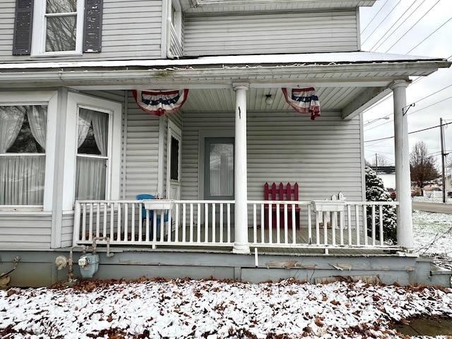 snow covered property entrance with covered porch