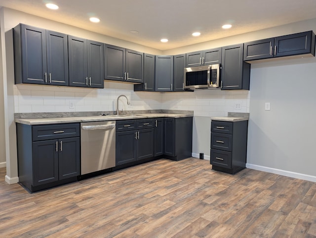 kitchen featuring backsplash, sink, stainless steel appliances, and light hardwood / wood-style floors