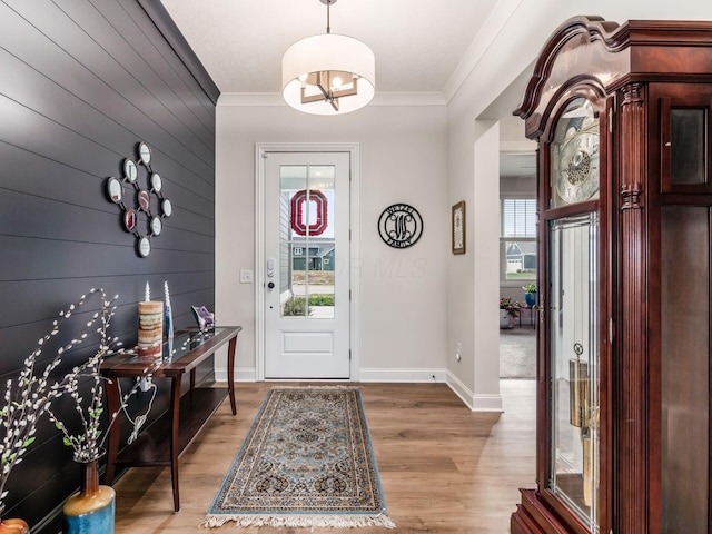 entryway featuring ornamental molding, light hardwood / wood-style floors, and wood walls