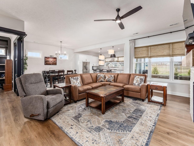 living room featuring ceiling fan with notable chandelier and light hardwood / wood-style floors