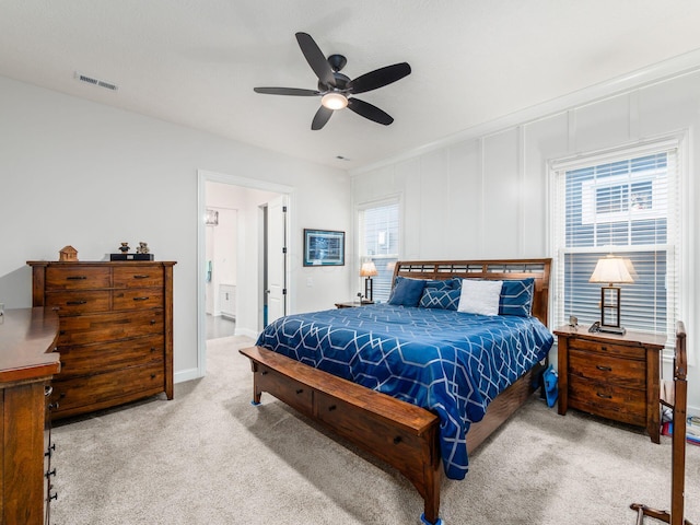 bedroom with ensuite bathroom, multiple windows, ceiling fan, and light colored carpet