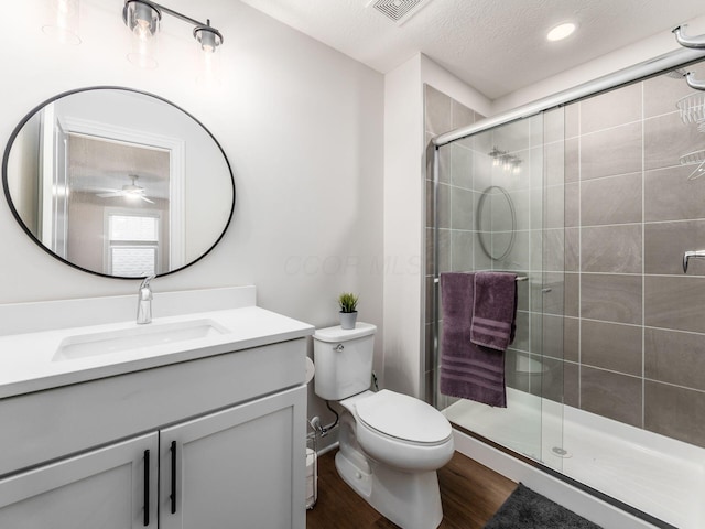 bathroom with a textured ceiling, toilet, wood-type flooring, walk in shower, and vanity