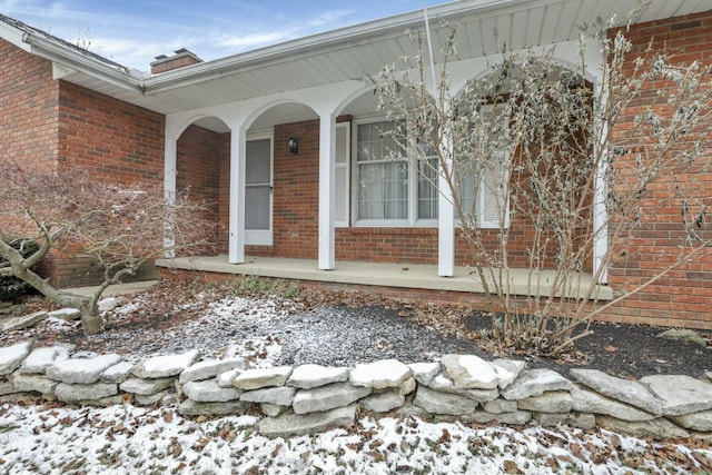 snow covered property entrance featuring a porch