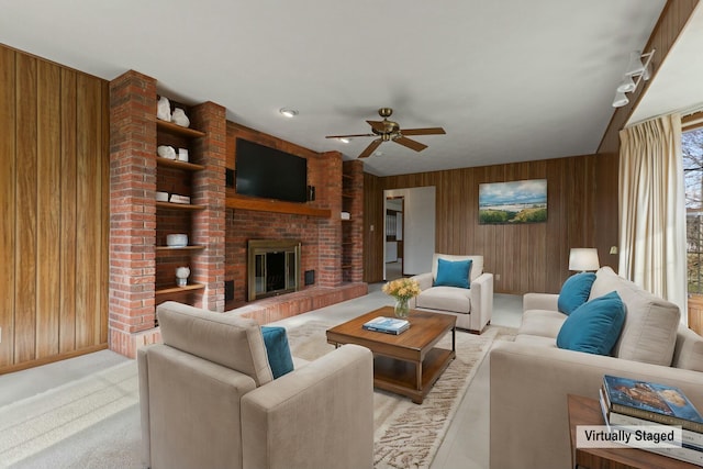 living room featuring ceiling fan, wood walls, and a fireplace