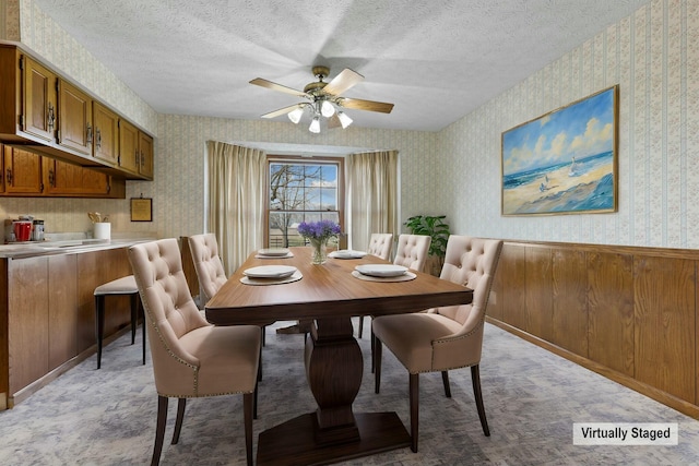 carpeted dining area with ceiling fan and a textured ceiling