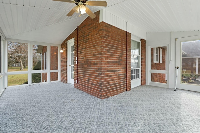 unfurnished sunroom featuring ceiling fan, a healthy amount of sunlight, and lofted ceiling