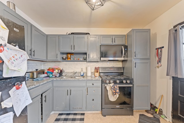 kitchen featuring gray cabinetry, sink, stainless steel appliances, light stone counters, and backsplash