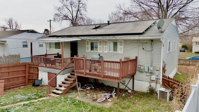 rear view of house featuring central AC unit, solar panels, and a wooden deck