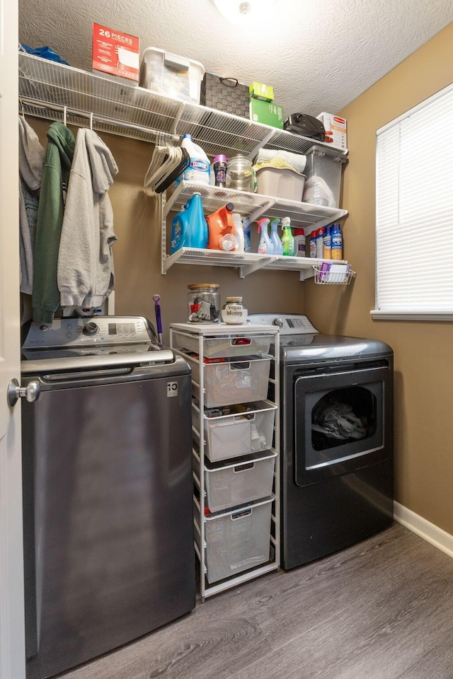 laundry area with a textured ceiling, laundry area, wood finished floors, baseboards, and washing machine and clothes dryer