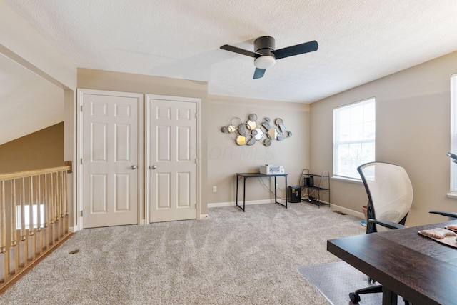 office area featuring light carpet, a textured ceiling, a ceiling fan, and baseboards