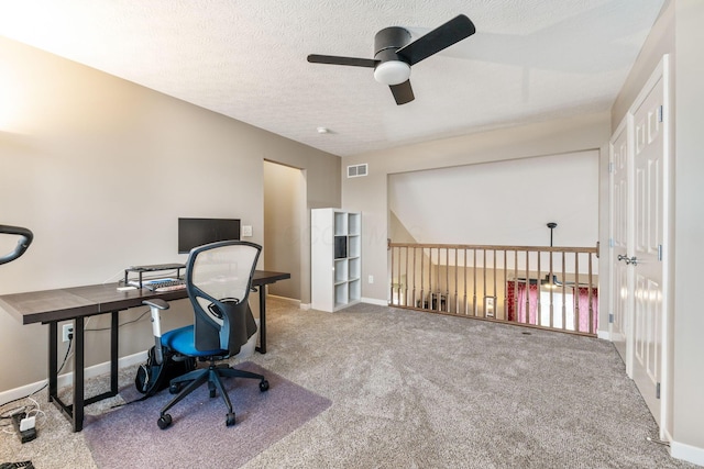 carpeted home office with visible vents, a textured ceiling, and baseboards