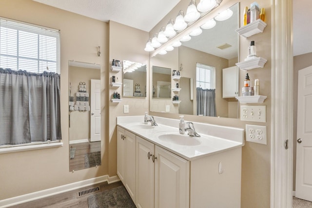 full bath featuring visible vents, a sink, baseboards, and double vanity