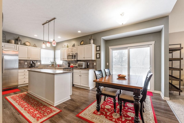 kitchen with stainless steel appliances, dark wood-type flooring, white cabinetry, a center island, and pendant lighting