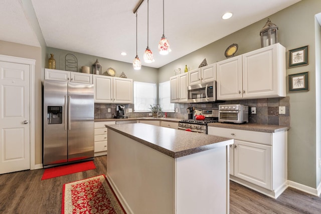 kitchen featuring white cabinetry, appliances with stainless steel finishes, a center island, tasteful backsplash, and decorative light fixtures