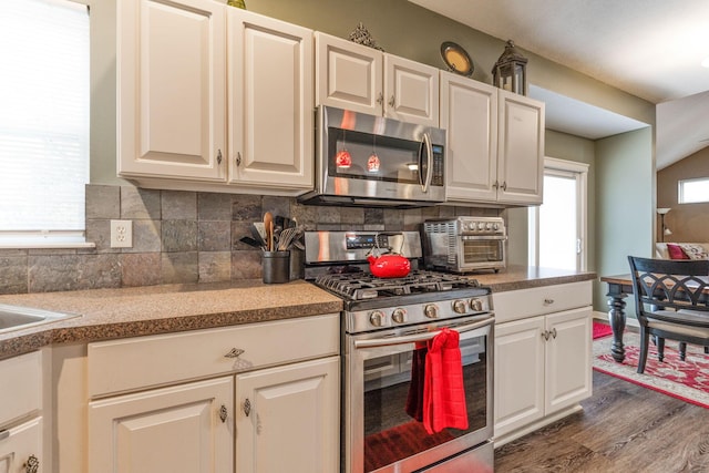 kitchen featuring appliances with stainless steel finishes, light countertops, dark wood-type flooring, and decorative backsplash