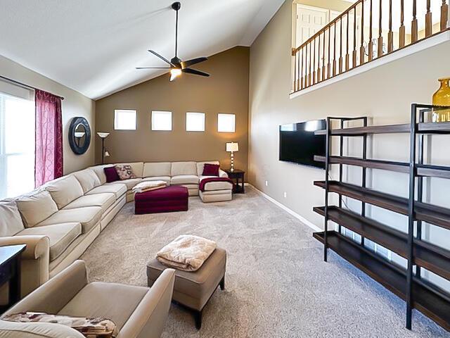 carpeted living room featuring high vaulted ceiling, ceiling fan, and baseboards