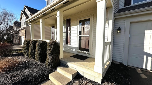 view of exterior entry with a garage and a porch