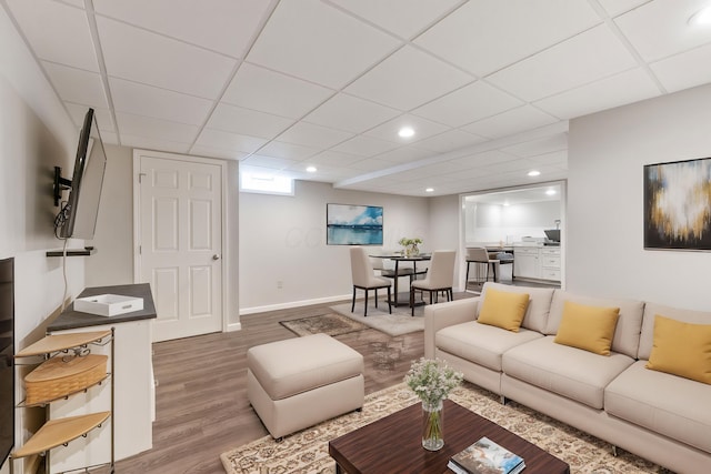 living room featuring recessed lighting, a drop ceiling, baseboards, and wood finished floors